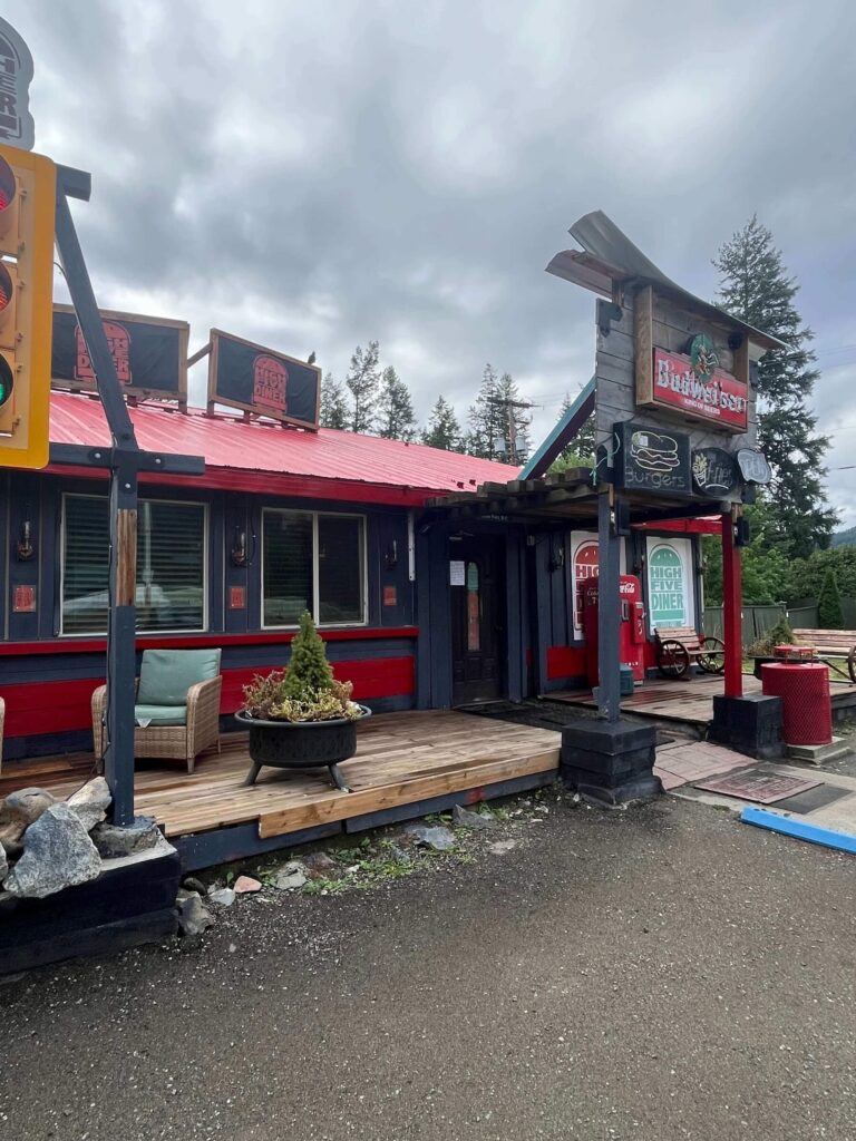 Rustic roadside diner with a red roof and outdoor seating at the High Five Diner in Little Fort, BC.